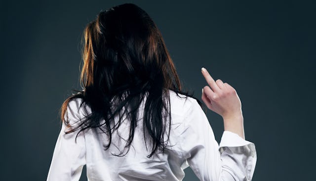 A brunette woman in a white button-up with her back turned, lifting her middle finger up
