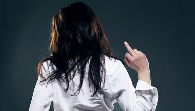 A brunette woman in a white button-up with her back turned, lifting her middle finger up 