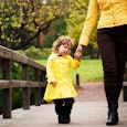 Mom and daughter are wearing yellow coats while taking a walk along a bridge 