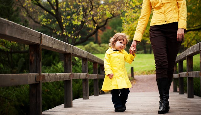A mom and a daughter in yellow coats, taking a walk along a bridge
