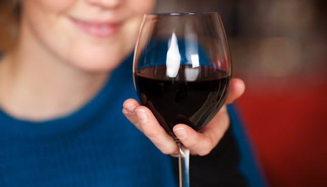 A close-up of a woman in menopause holding a glass of wine