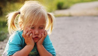 A blonde girl with pigtails, wearing a blue t-shirt and feeling sad after her bad behavior