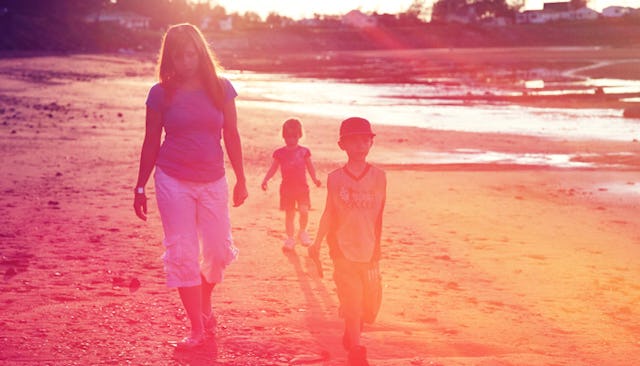 A single mom at the beach walking with her two kids