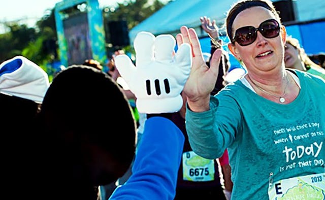 A woman high-fiving a Mickey Mouse mascot while running a marathon