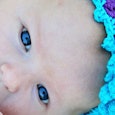 A baby with a blue cloth headband with a floral pattern