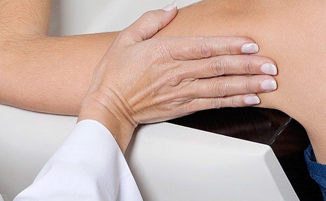 A doctor's hand on woman's upper armpit area as checking for breast cancer