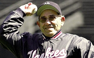 A famous American professional baseball catcher Yogi Berra, holding a baseball in his hand while smi...