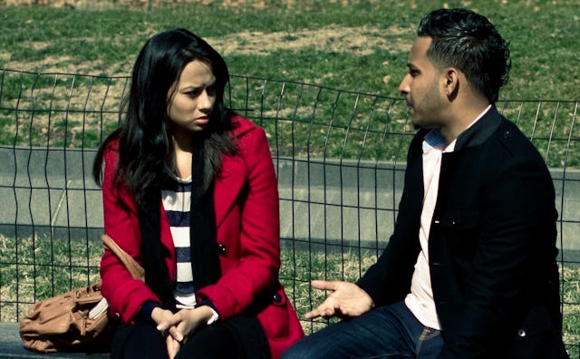 A young couple sitting down on a bench while arguing