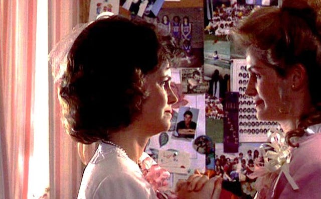 A southern girl and her mother facing each other in front of a board covered in various high school ...