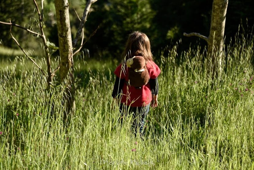 child walking through grass, back to camera