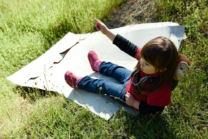 child about to slide down a mound on a piece of cardboard