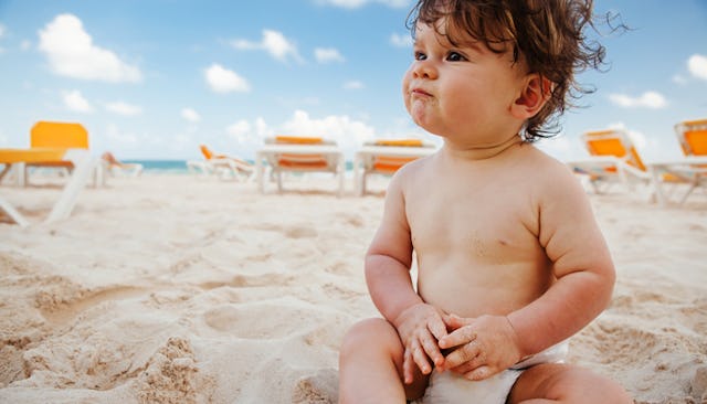 A sad baby boy wearing diapers on a beach