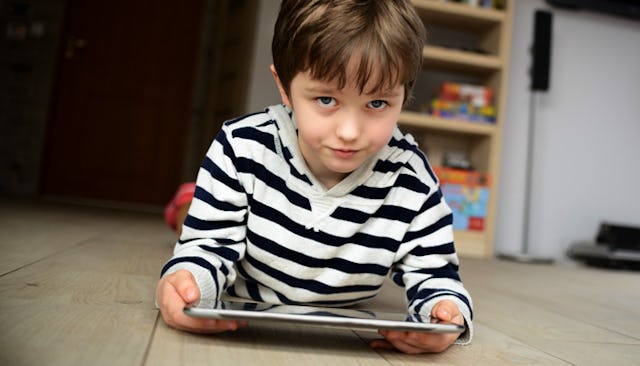 A 6-year-old boy in a black and white striped hoodie lying down on the floor and searching something...