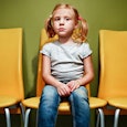 Blonde girl sitting on a yellow chair while waiting for a psychiatrist appointment in a waiting room...