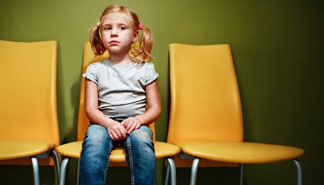 A blonde girl sitting on a yellow chair while waiting for a psychiatrist appointment in a waiting ro...
