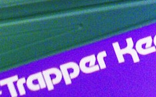 White "Trapper Ke" text on a blue surface from the 1980s