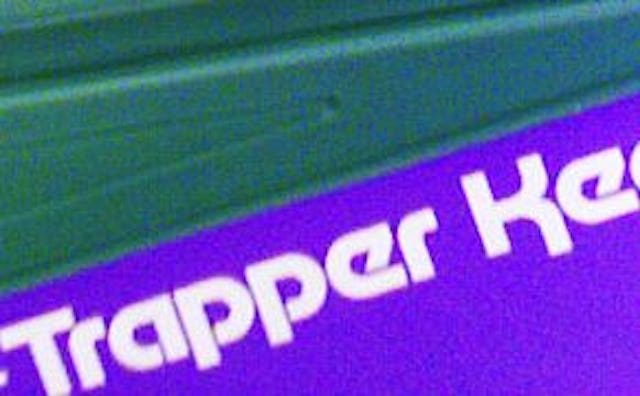 A white "Trapper Keeper" logo on a blue surface from the 1980s