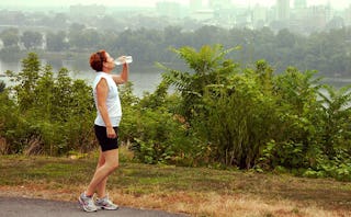 A 40-year-old woman taking a break from her run outside while drinking water