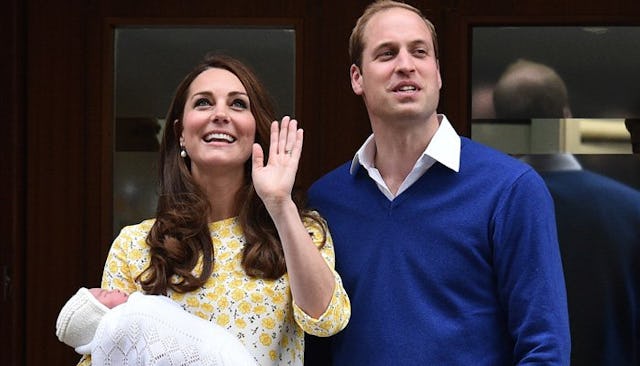 Kate Middleton in a yellow floral dress holding newborn Princess while standing and smiling next to ...