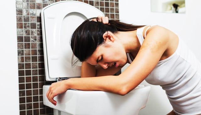 A woman leaning over a toilet seat who doesn't know if she is pregnant or if it was just bad food