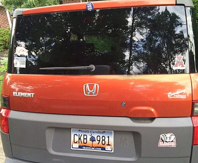 An orange Honda Element car with an Obama sticker on the back