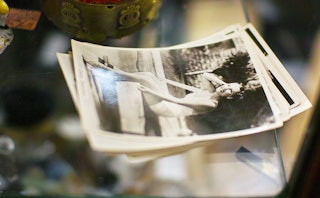 Black and white photograph of a woman on top of stack of photographs on a glass table
