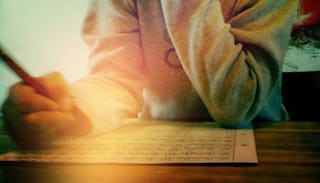 A child sitting and doing his homework on a wooden desk