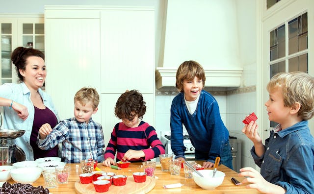 A mother and 4 boys during her son's sleepover party sitting at a dining table with various snacks