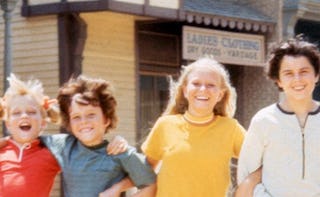 Four kids pictured together, two of them are teens and all are smiling and having fun.
