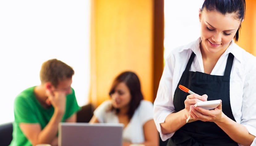 A waitress taking an order while two people behind her are studying