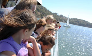 A parent chaperoning a group of middle-schoolers, enjoying a sunny boat ride during the school field...