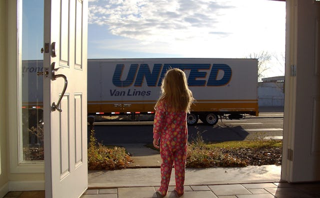 The back of a small girl standing at the entrance of a house waving to a big truck, 'United Van Line...