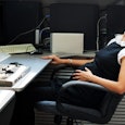 Pregnant lady in the office lying down on a chair in front of her desk