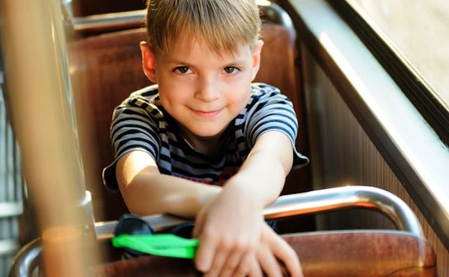 A kid on a field trip smiling while sitting in a bus