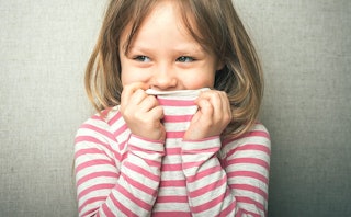 A girl covering her mouth with her white and pink striped shirt