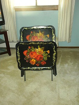 An ornate black tv table with drawn on flowers