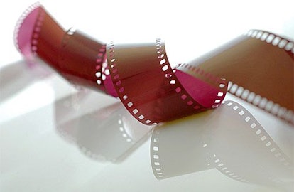 A strip of film twisting on a white reflective surface