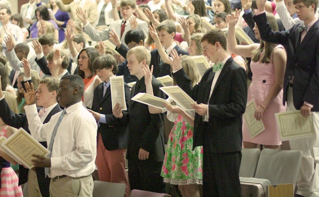 Numerous students holding their diplomas in an auditorium during their first middle school awards ce...