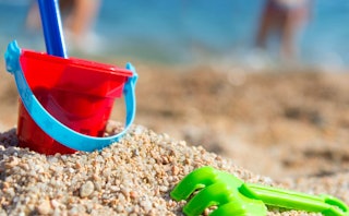 Plastic bucket and rake on the sand.