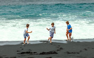 Three boys playing and running on a beach