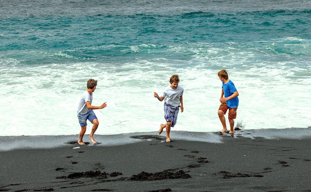 Three boys playing and running on a beach