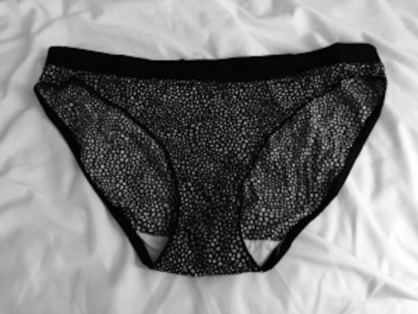 Black mesh-lace underwear on white bed sheets