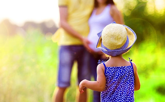 A kid with a straw fedora walking toward parents in their 30s; a father resting his hand on the moth...