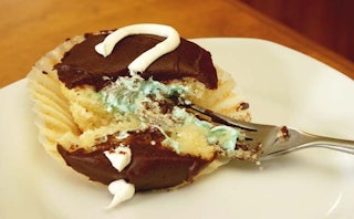 A glazed chocolate cupcake with blue filling at a gender reveal party