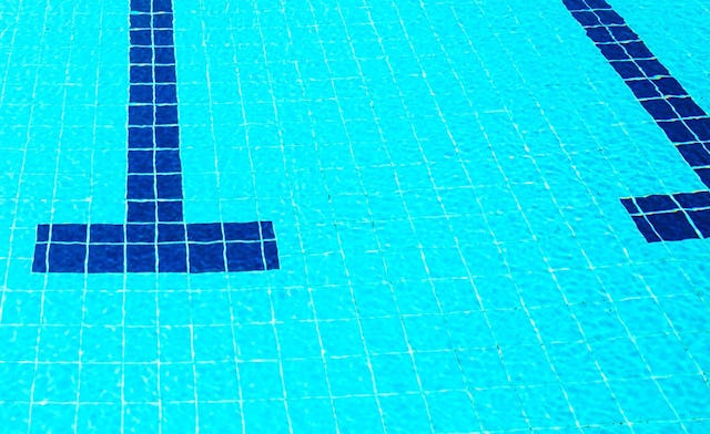 A big swimming pool with clean water and teal tiles.