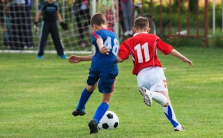Two boys playing soccer on a soccer field