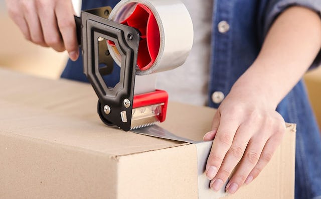 A mom packing and taping a box during house moving