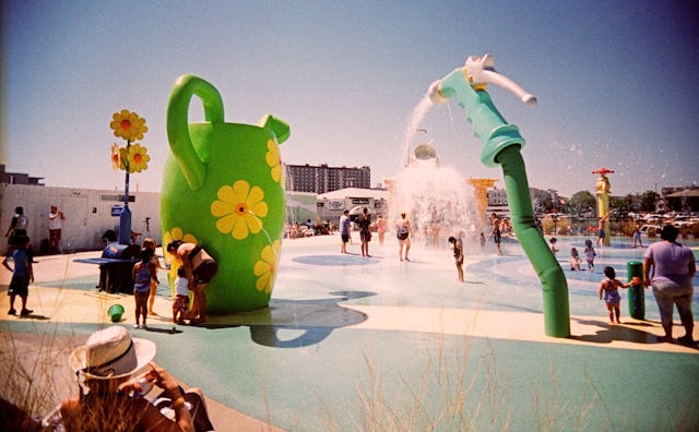 Several people standing and walking around a water park during day time