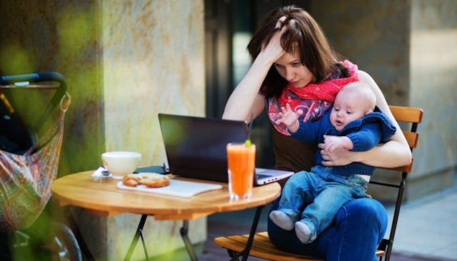 A mother with a baby on her lap holding her hand on her hand while looking at a laptop