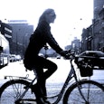 A blonde lady driving a bicycle on a street of a city whose dad is gone and she is getting divorced ...